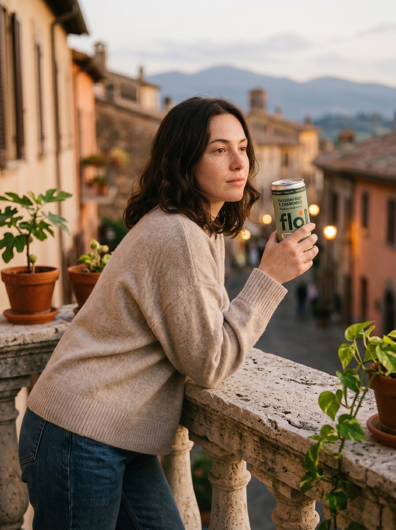 Woman on a stone balcony at sunset holding Calm Core, an old European town receding behind her