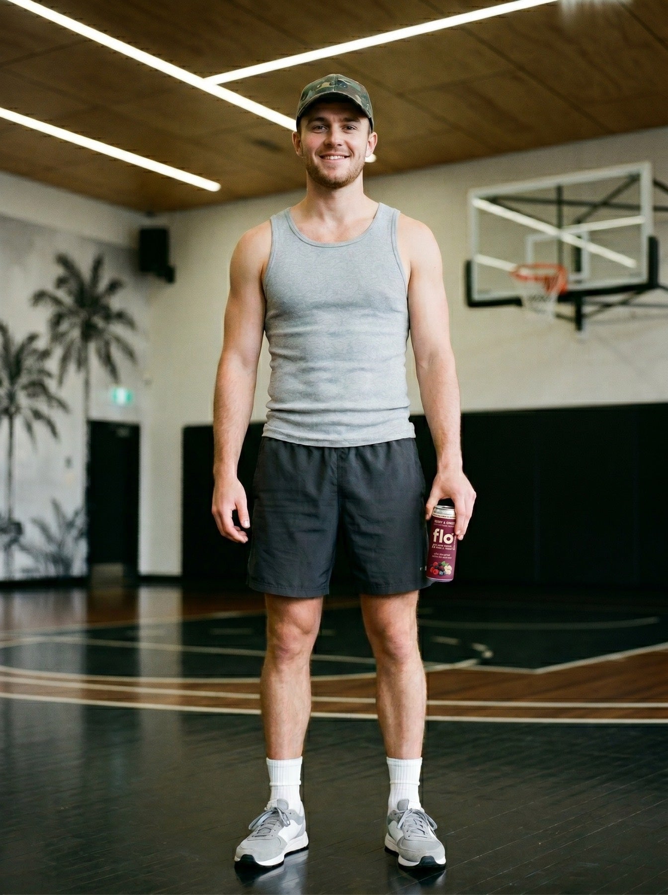 Young man in a private gym holding up Restore Rush, basketball hoop visible behind
